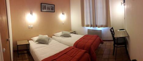Habitación de hotel con dos camas, un escritorio y una silla.