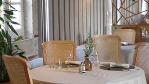 Un comedor con una mesa redonda dispuesta para cuatro personas, rodeada de sillas de mimbre.