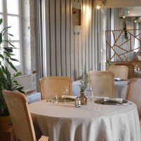 Un comedor con una mesa redonda dispuesta para cuatro personas, rodeada de sillas de mimbre.