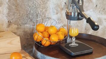 A manual citrus press with oranges and juice, a wooden cutting board, and a metal bowl.