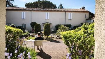 Un patio con un camino de grava, plantas en macetas y un edificio con tejado de baldosas.
