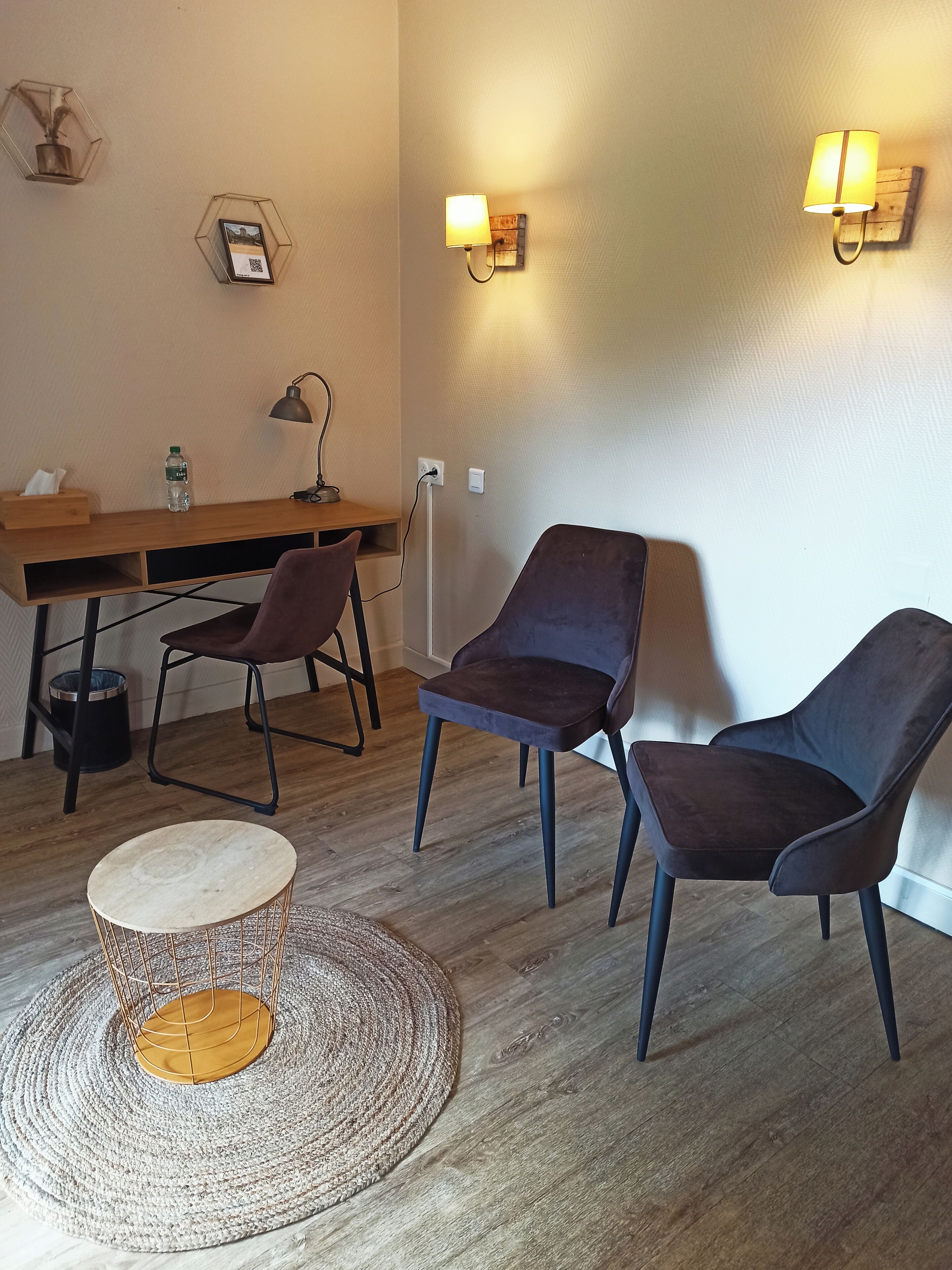 Quarto moderno com uma escrivaninha de madeira, duas cadeiras, uma luminária e iluminação embutida.