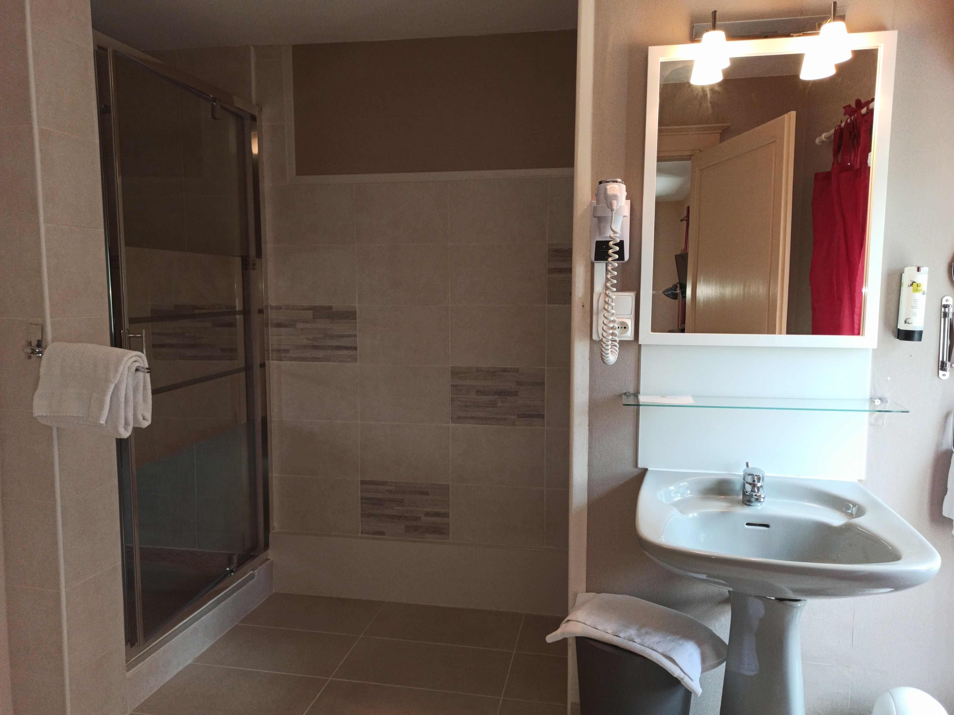 Un baño con cabina de ducha de vidrio, lavamanos y espejo con iluminación.