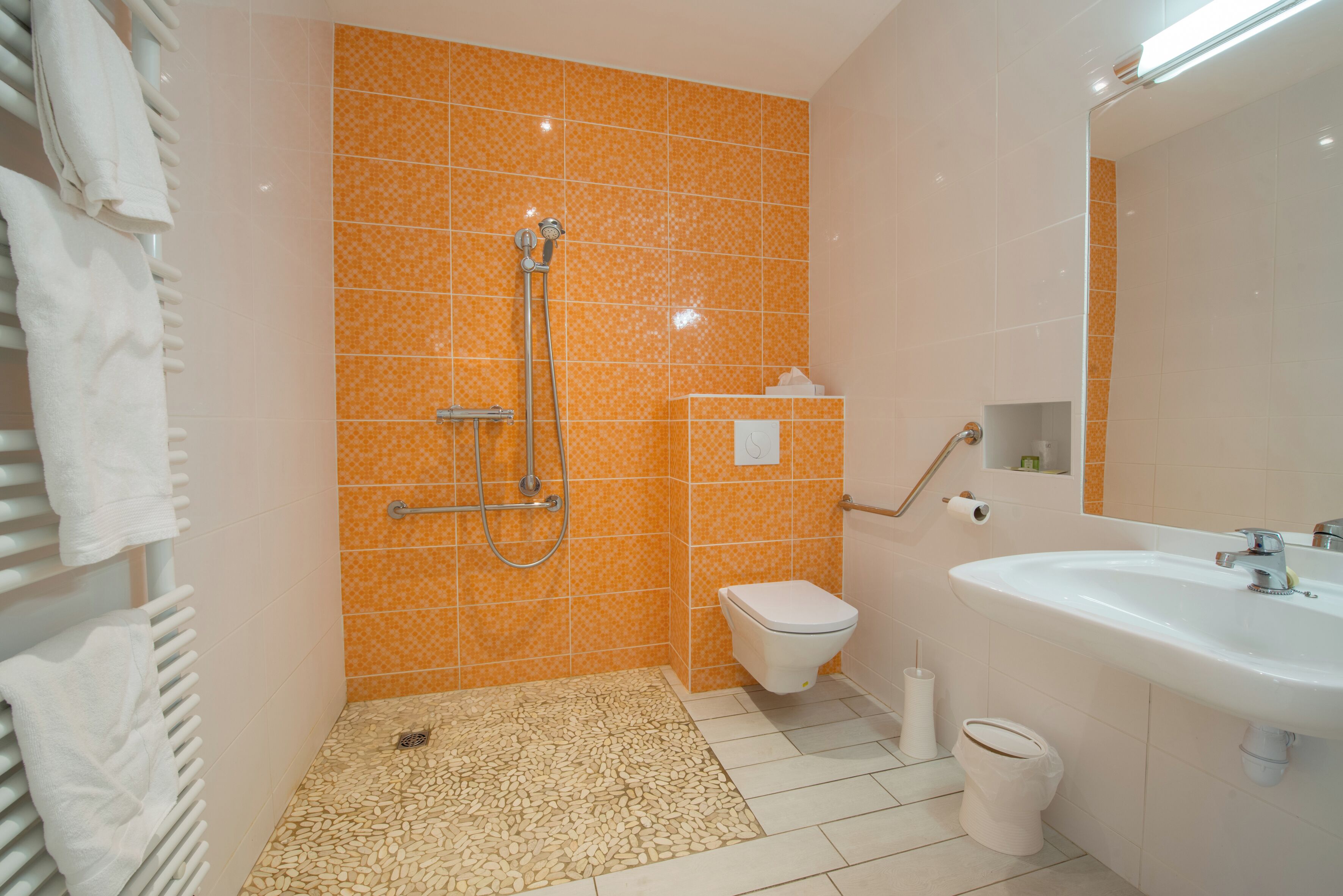 Un baño con ducha, inodoro, lavabo y perchero para toallas.