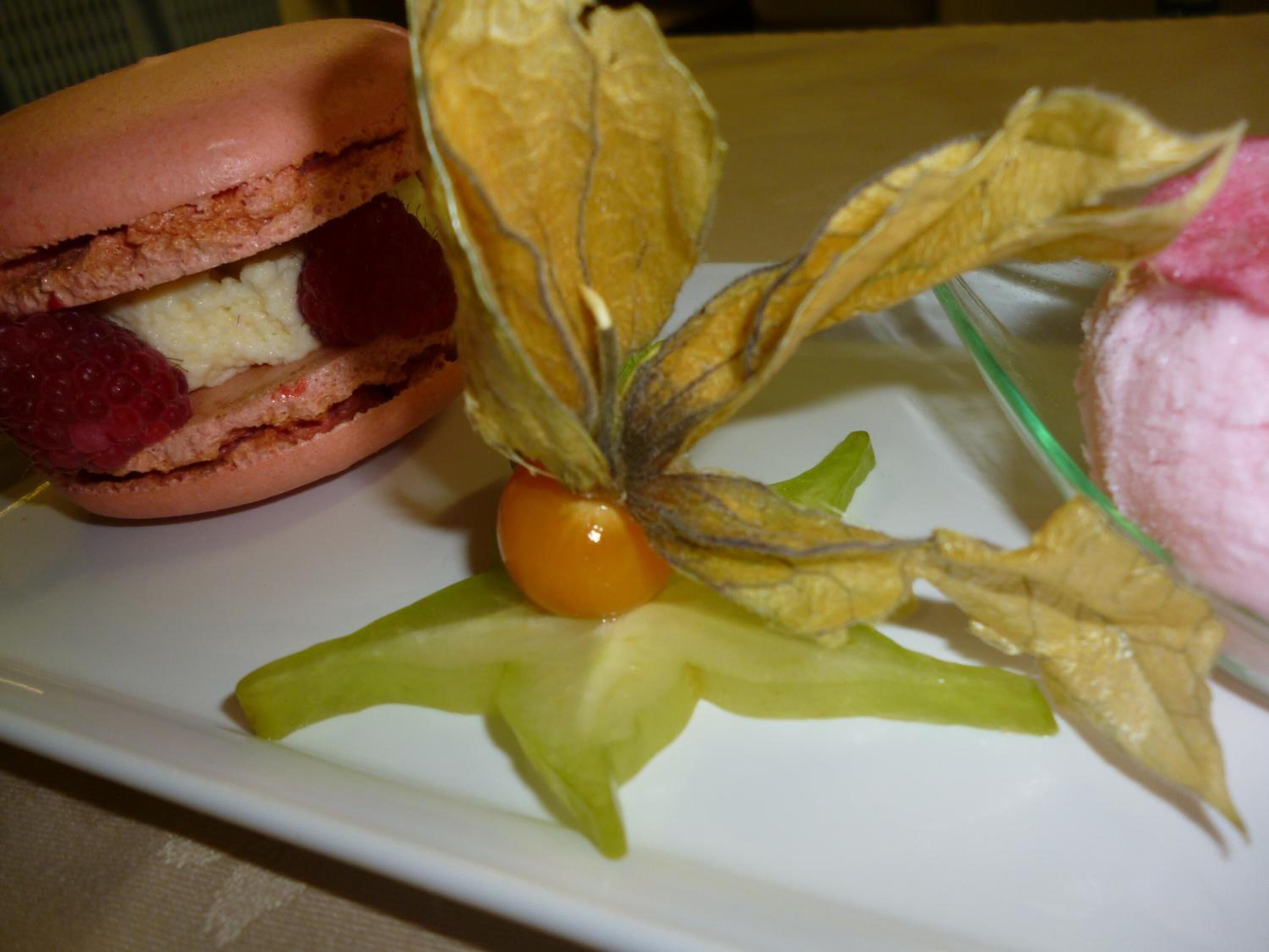 A dessert plate with a pastry sandwich, a decorative flower arrangement, and a scoop of ice cream.