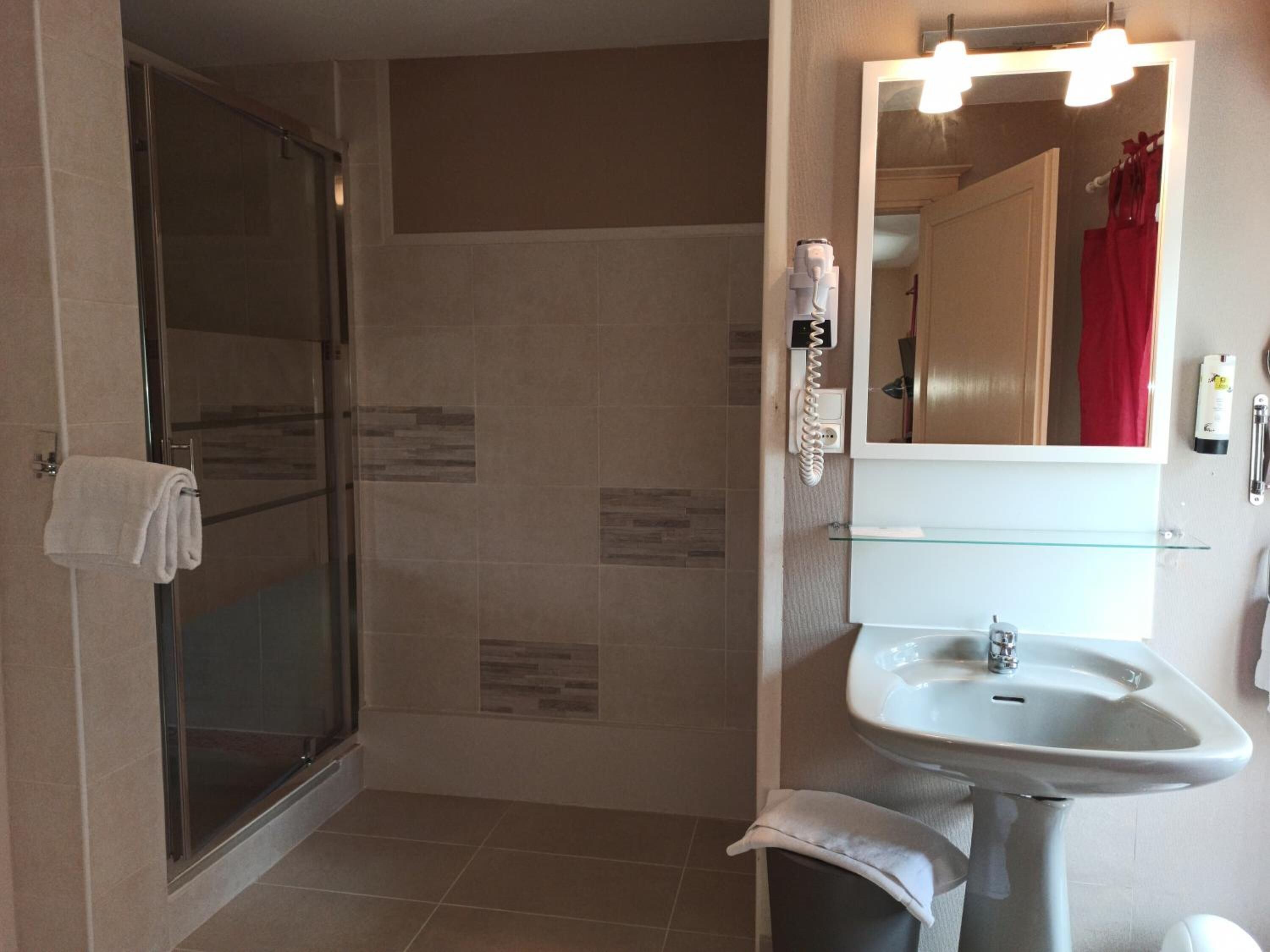 Une salle de bain moderne avec une douche à parois de verre, un lavabo blanc et un miroir avec éclairage intégré.