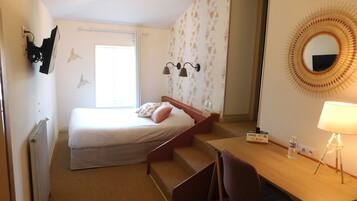 Een hotelkamer met een bed, een bureau, een stoel, een spiegel en een radiator.