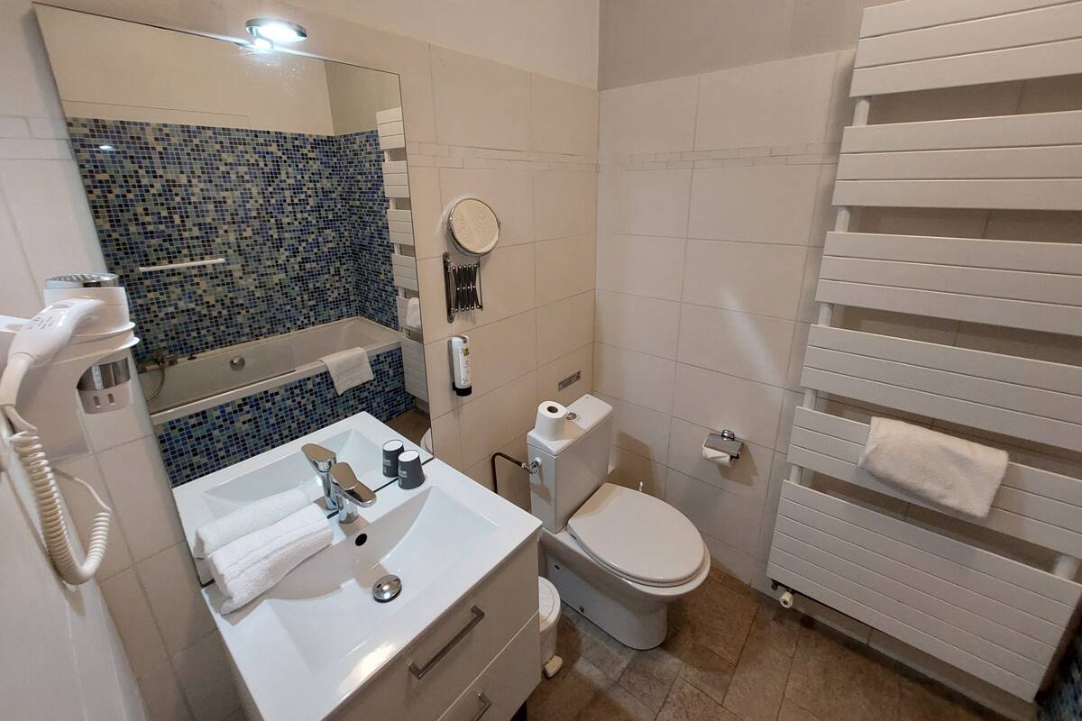 A bathroom with a white sink, mirror, toilet, and towel rack.