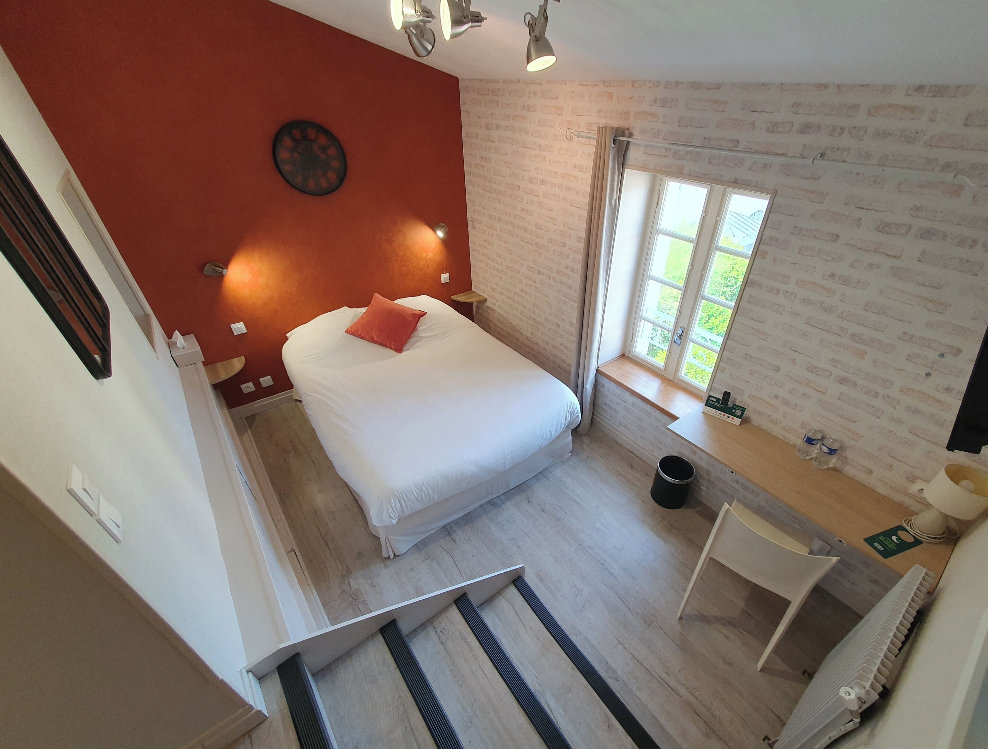 A bedroom with a bed, a window, a radiator, and a small table.