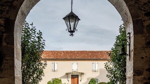 Un arco de entrada a un edificio con tejado de azulejos, una campana y un letrero que indica la recepción.
