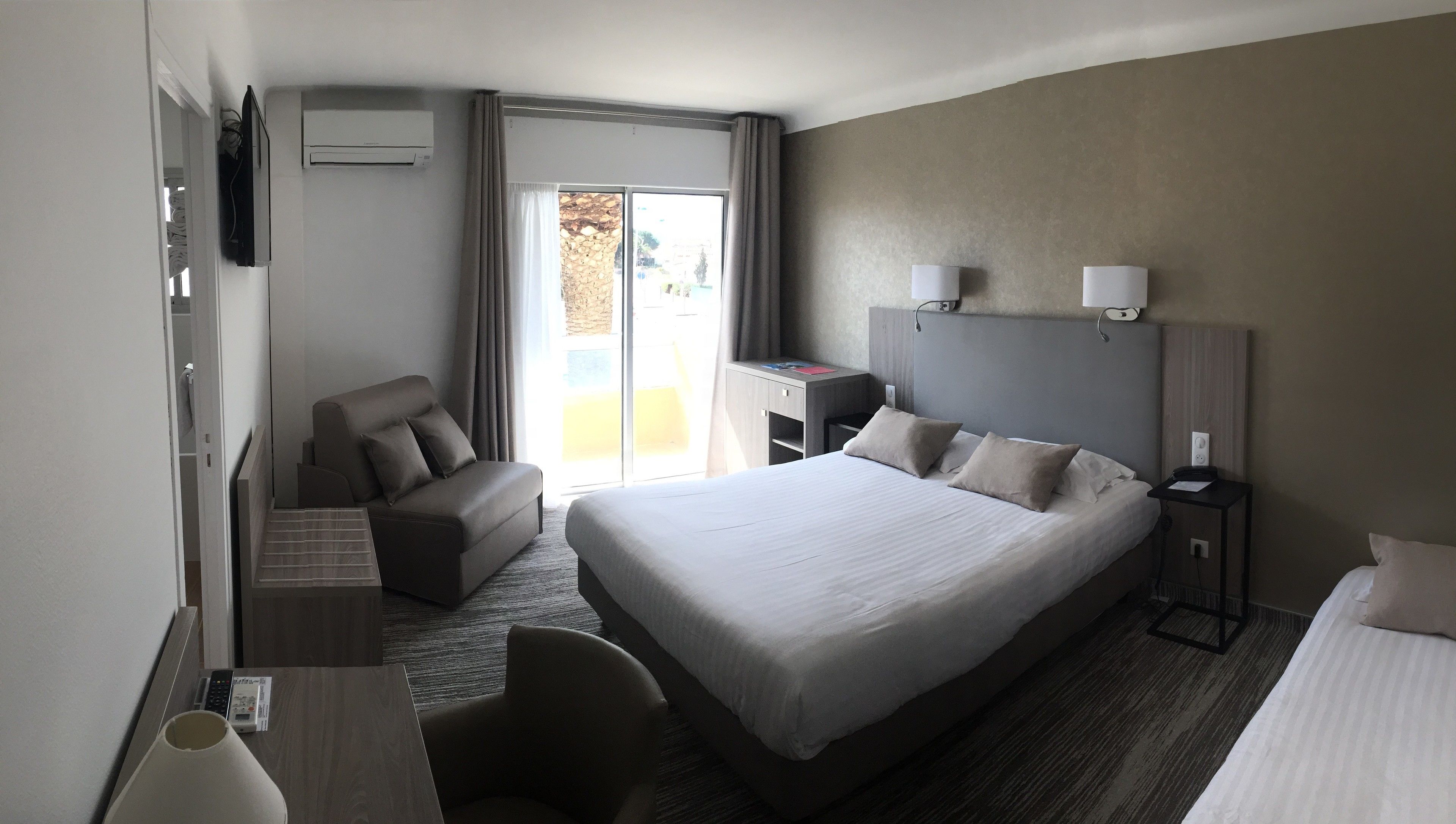 Habitació d'hotel amb un llit gran, una taula, una cadira i un televisor.