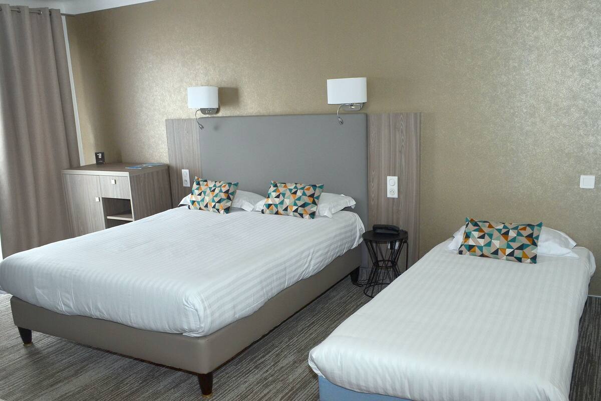 A hotel room with two beds, a desk, and a chair.