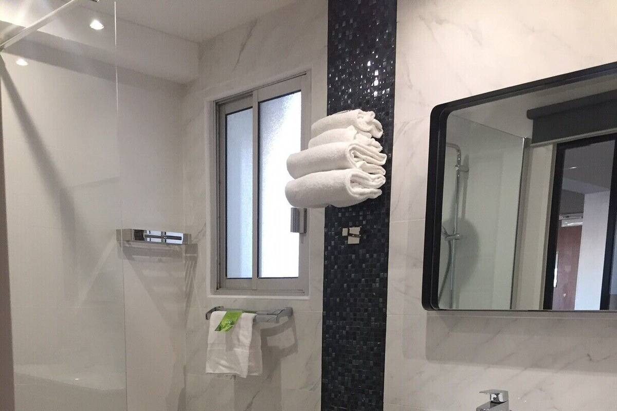 A modern bathroom with a glass shower enclosure, a vanity with a dark wood finish, and a large mirror.