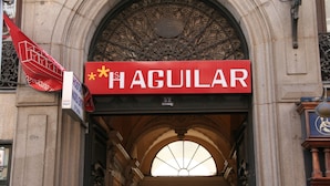 Entrada de un hotel con un cartel grande que dice "HAGUILAR" y un cartel más pequeño que indica la habitación número 32.