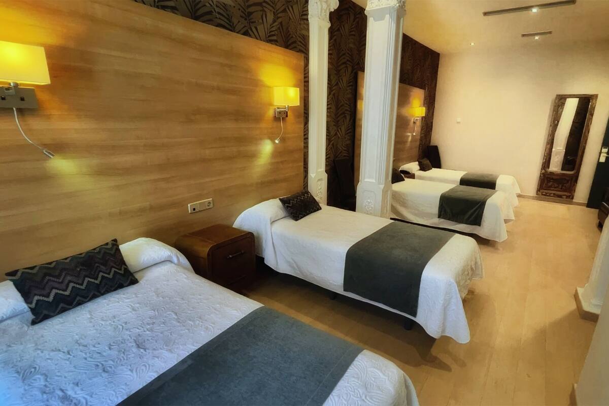 Quarto de hotel com duas camas, uma cabeceira de madeira e um espelho.