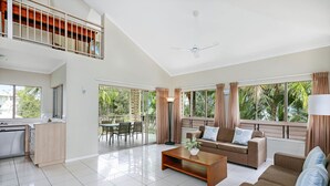 A spacious living area with a sofa set, a coffee table, and a dining area with chairs and a table. - Mantra Amphora (Palm Cove)