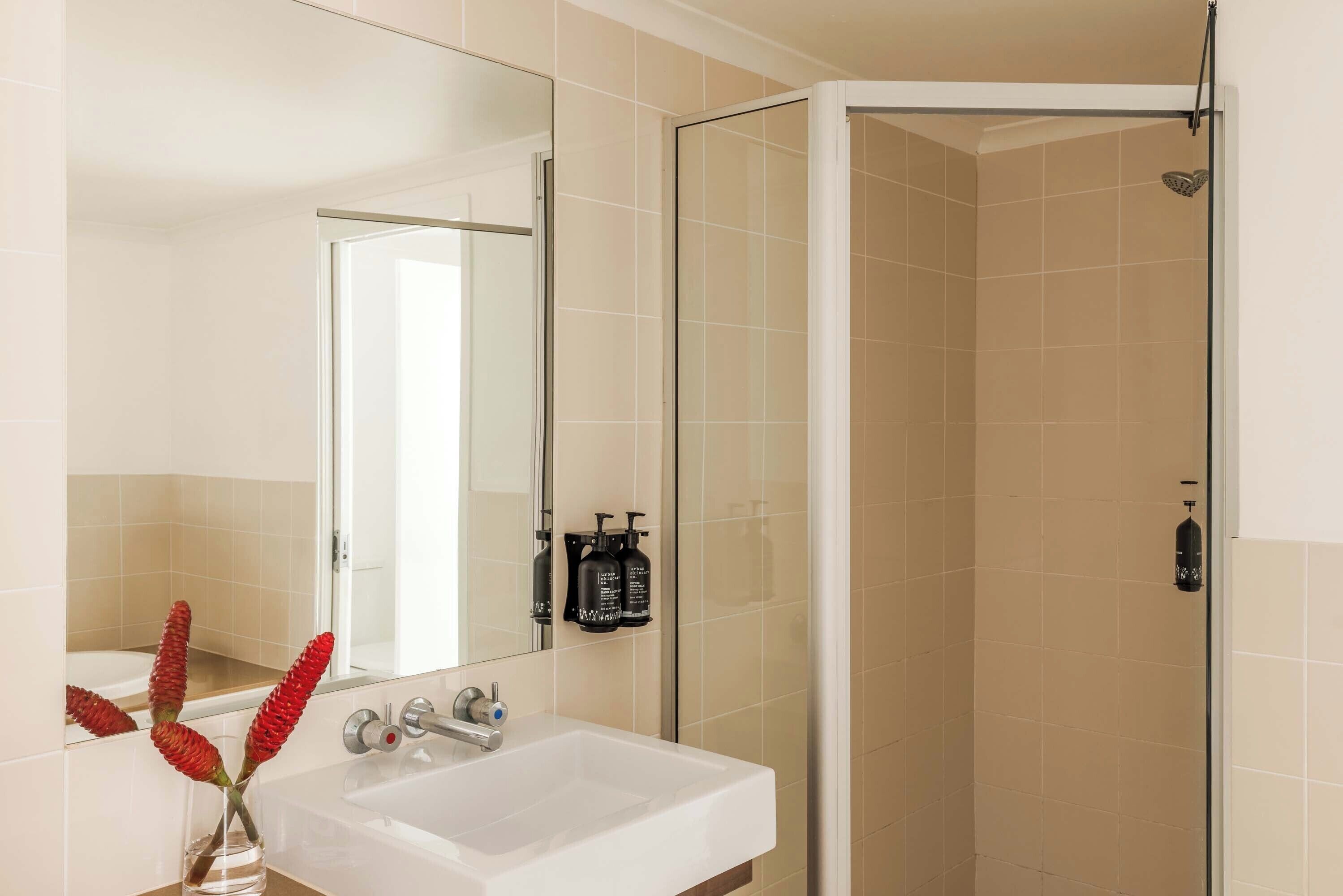 A bathroom with a white sink, a mirror, and a shower area.