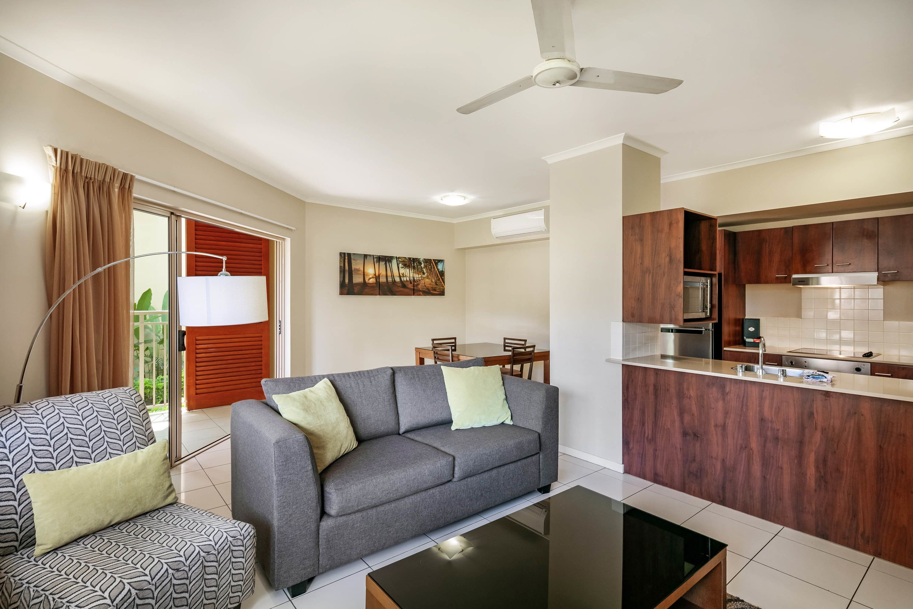 A modern living room with a grey sofa, a patterned armchair, and a glass coffee table.
