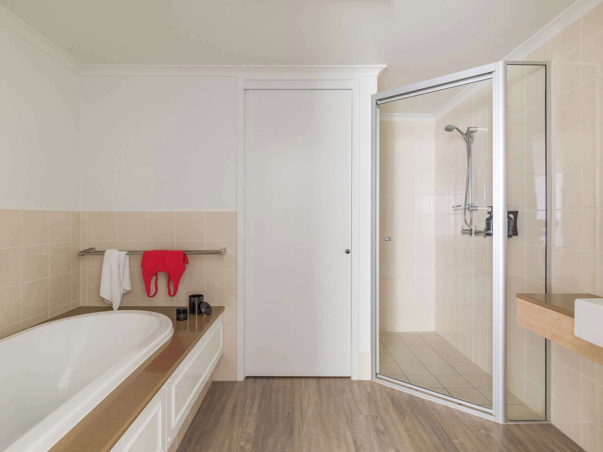 A modern bathroom with a bathtub, a glass-enclosed shower, and a white door.