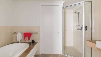 A modern bathroom with a bathtub, a glass-enclosed shower, and a white door.