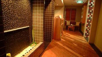 Stylish corridor with a dark mosaic wall, wooden bench, and a small table with chair.