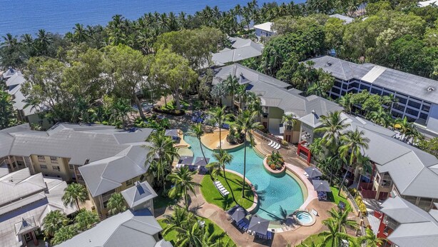 A resort with a central swimming pool, multiple buildings, and a view of the ocean. - Mantra Amphora (Palm Cove)