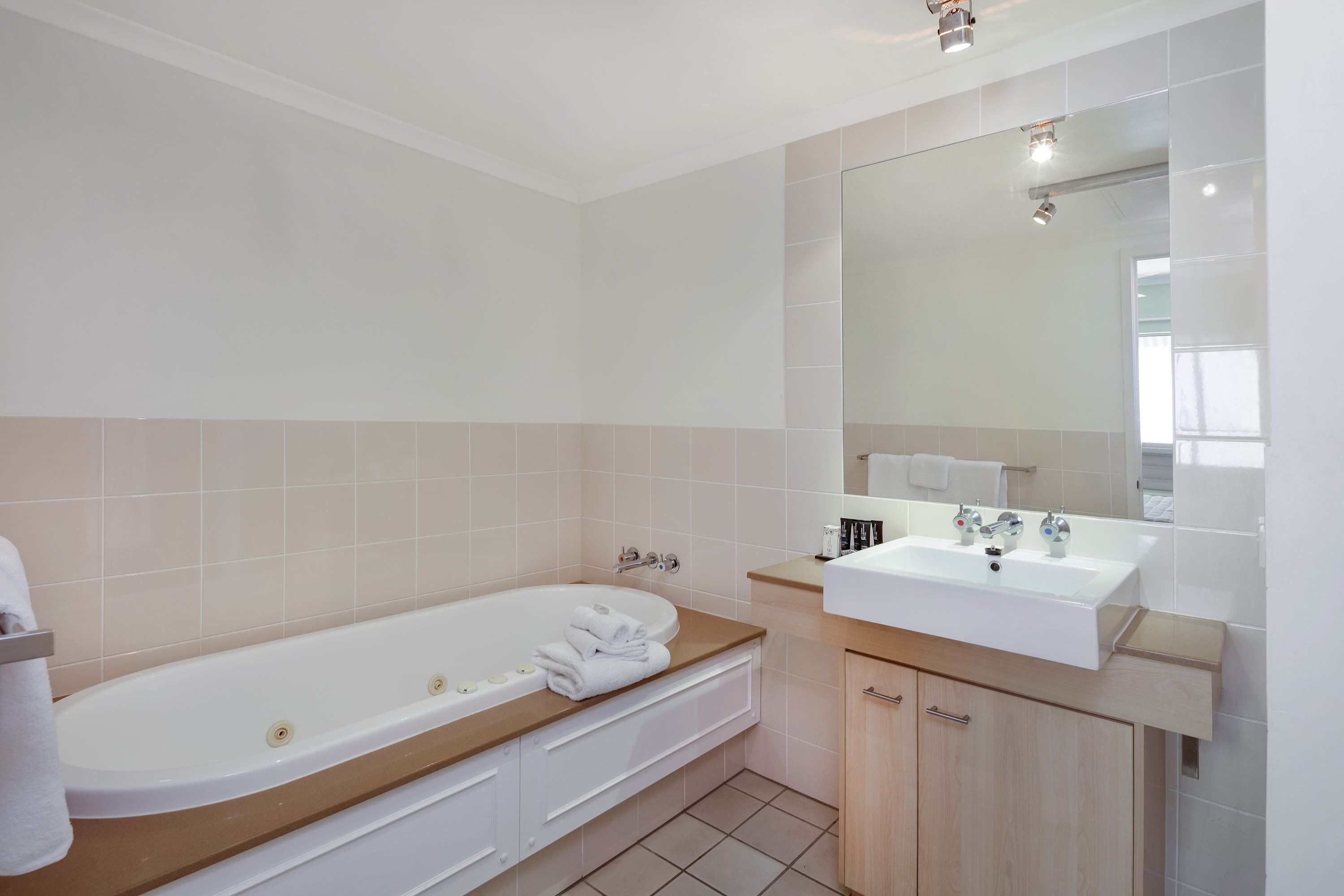 A modern bathroom with a freestanding bathtub, a vanity with a sink, and a large mirror.