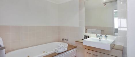 A modern bathroom with a freestanding bathtub, a vanity with a sink, and a large mirror.