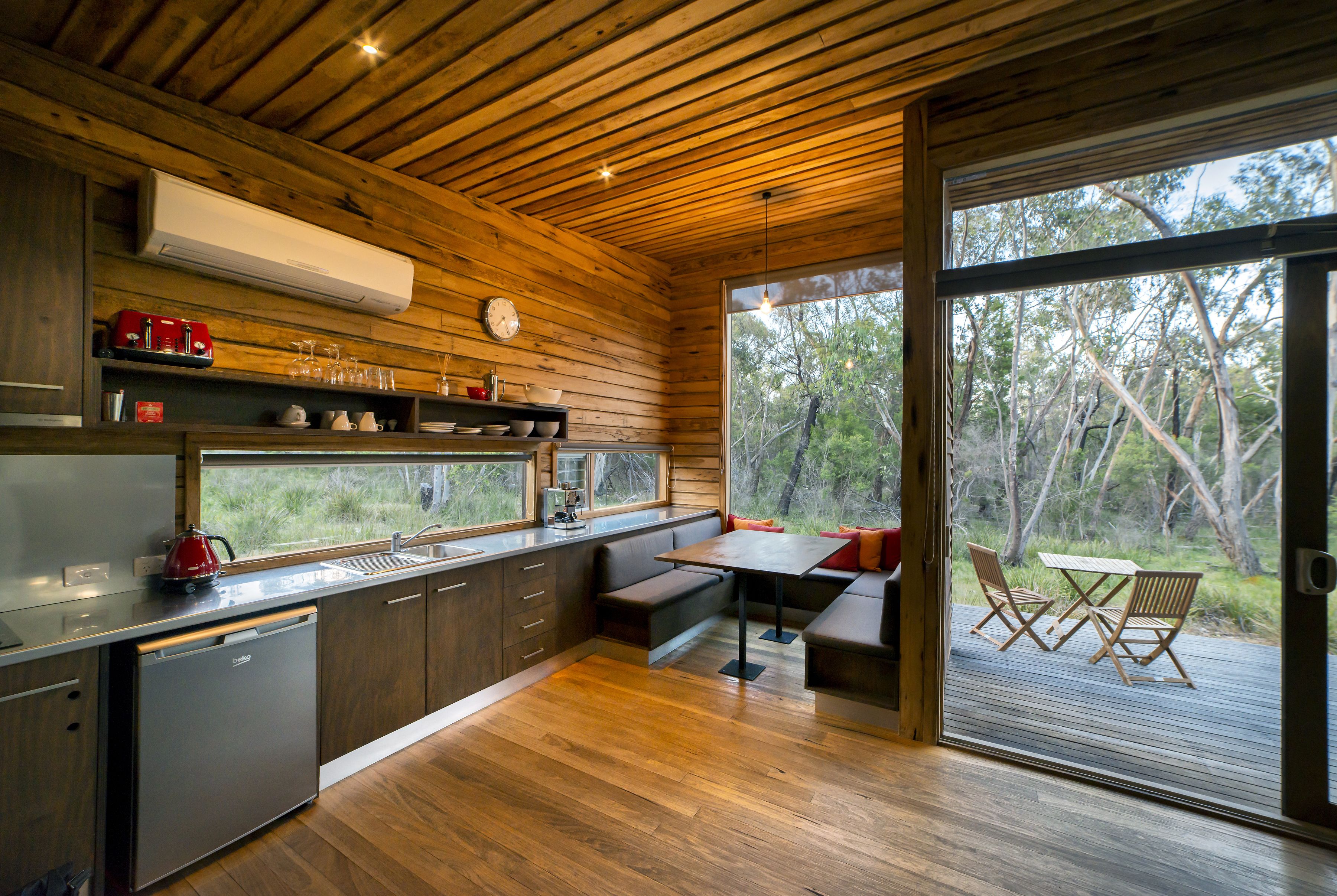 Une cuisine moderne avec des meubles en bois, un lave-vaisselle encastré et une grande fenêtre donnant sur une terrasse.