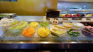 Un buffet proposant une variété de plats, notamment des salades, des céréales et des sauces.