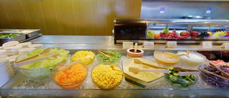 Un bufé con diversas opciones de comida, entre ellas ensaladas, cereales y salsas.