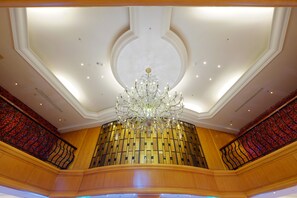 Un intérieur somptueux, avec un grand lustre, des boiseries et une balustrade rouge à motifs.
