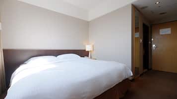 Une chambre d’hôtel avec un grand lit, une table de chevet avec une lampe et une porte en bois.