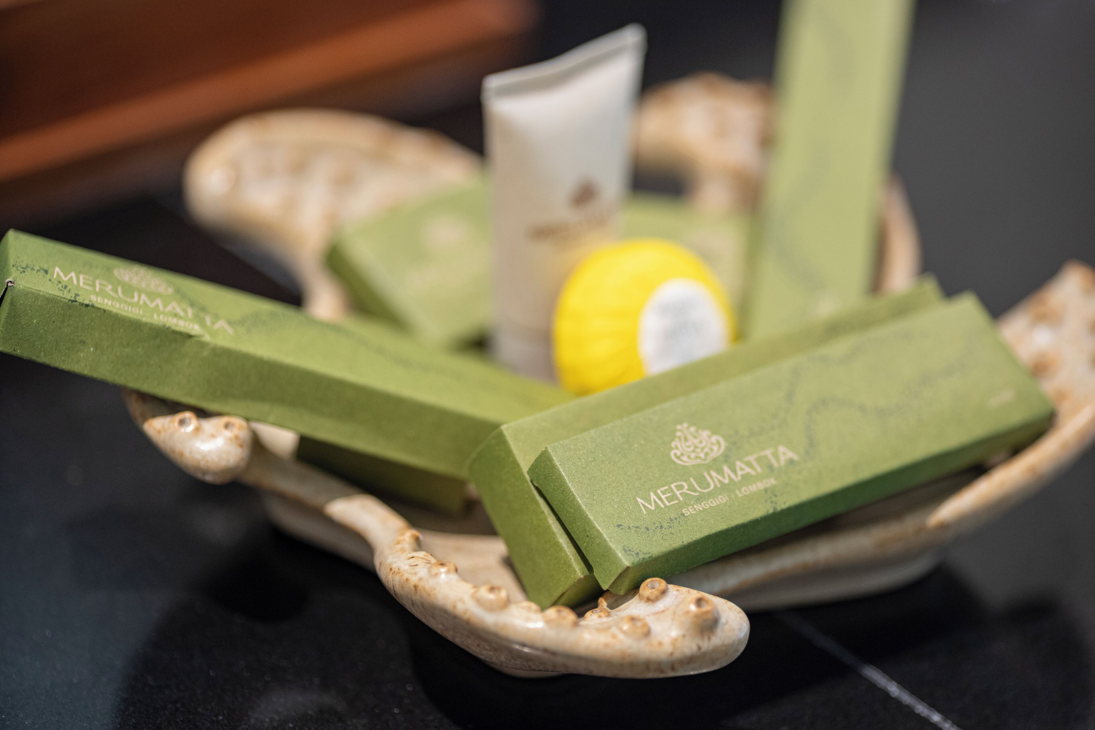 Un savon vert en forme de pain, portant l’inscription « MERUMATTA », et un citron sur une assiette en céramique.