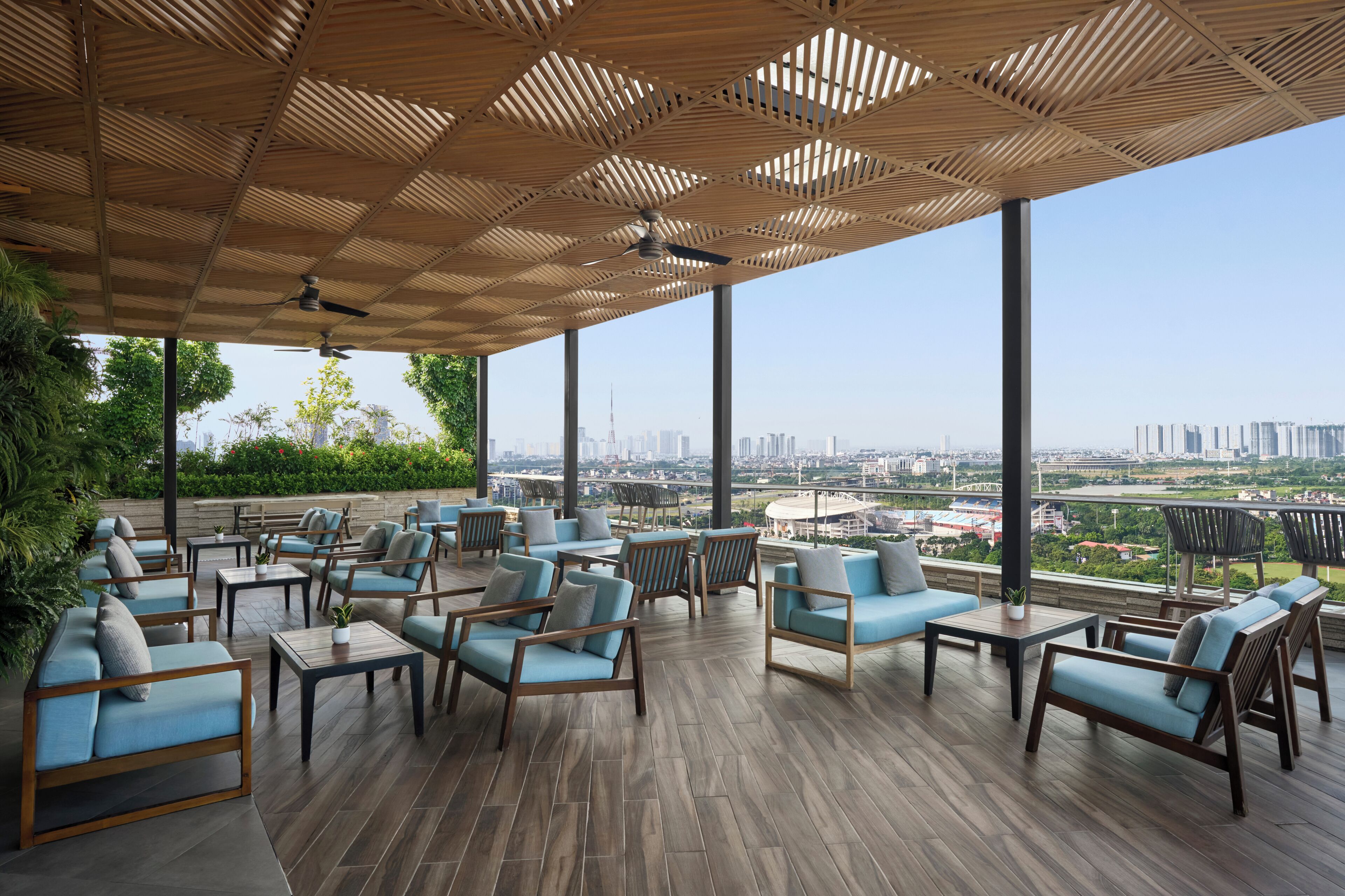 A covered outdoor seating area with multiple chairs and tables, large windows offering a city view.