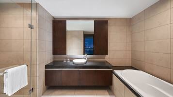 A modern bathroom with a glass shower enclosure, a large mirror, a built-in sink, and a bathtub.