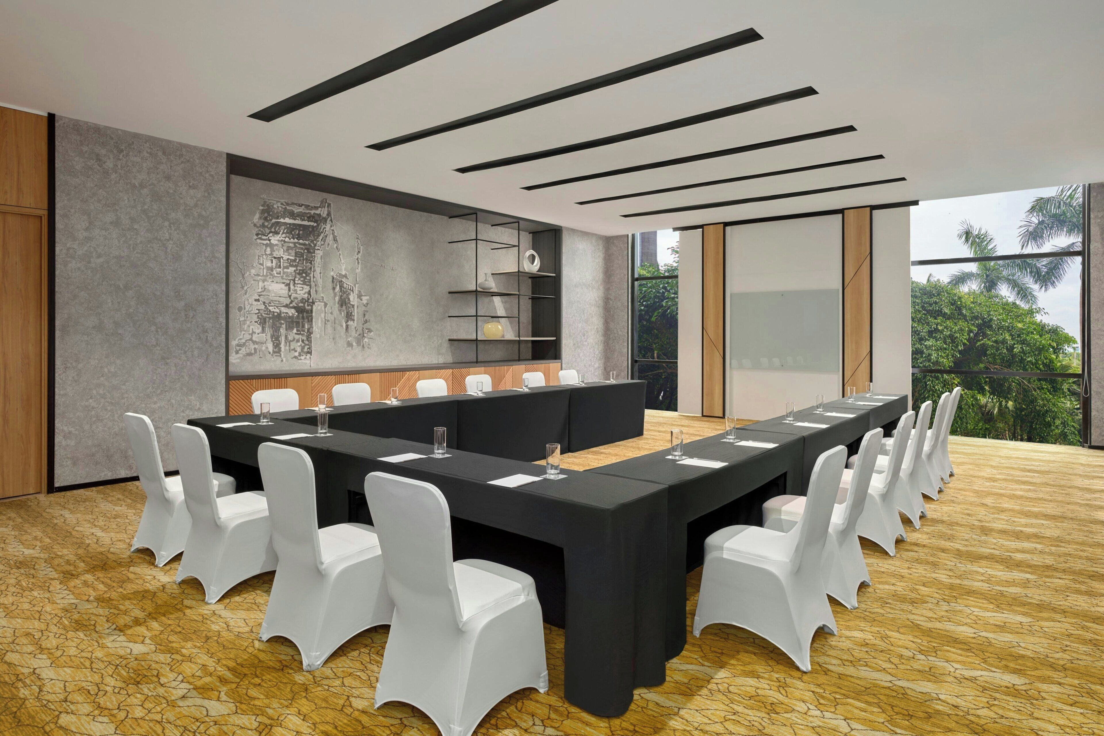 Une salle de conférence dotée d’une longue table, de chaises blanches et d’un plafond au design moderne.