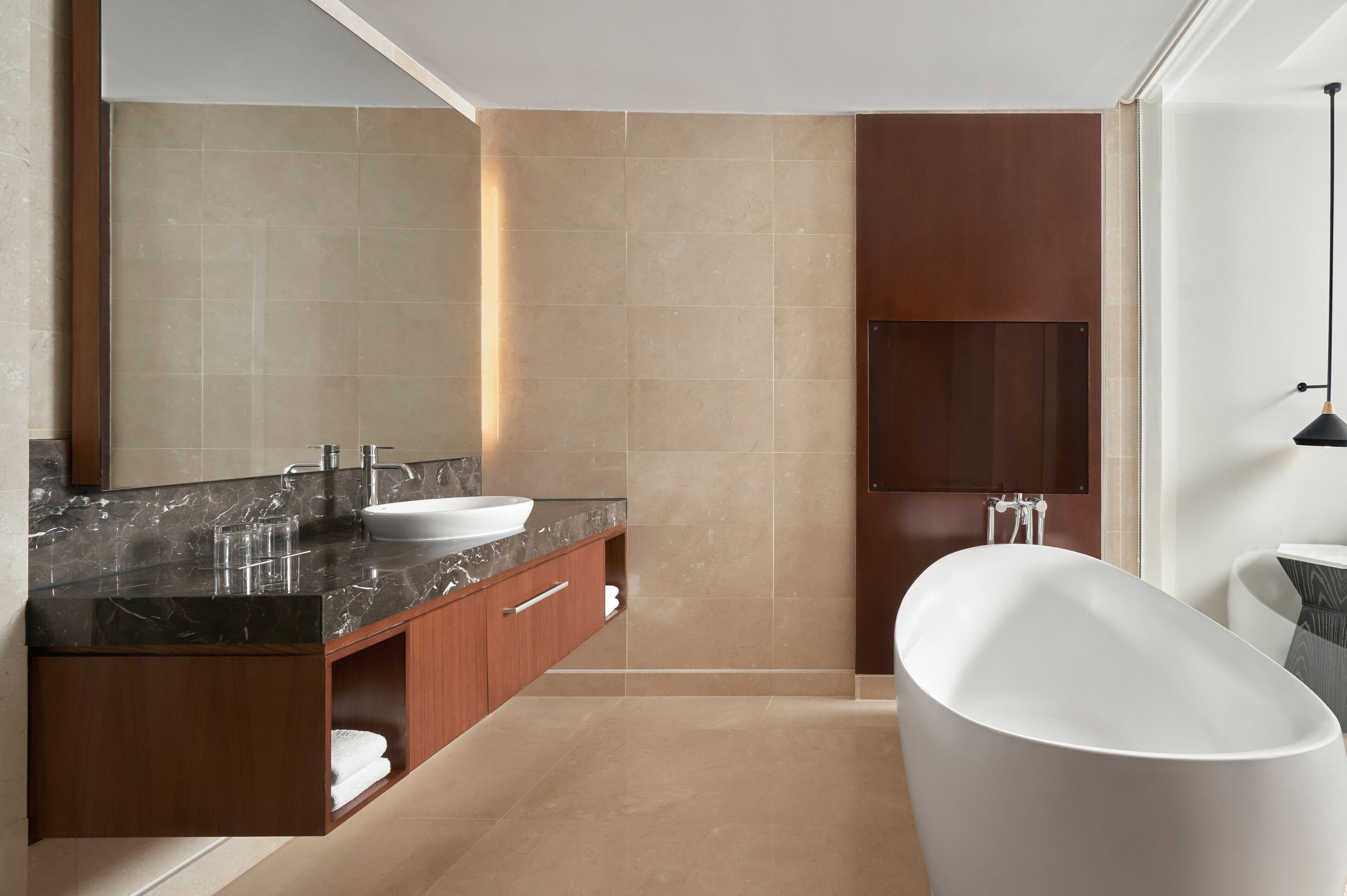 Une salle de bain moderne avec une baignoire sur pieds, un grand miroir et un plan de toilette en marbre foncé.