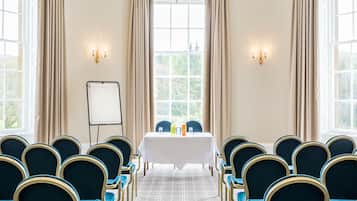 A conference room with a white table, blue chairs, and a projector screen.