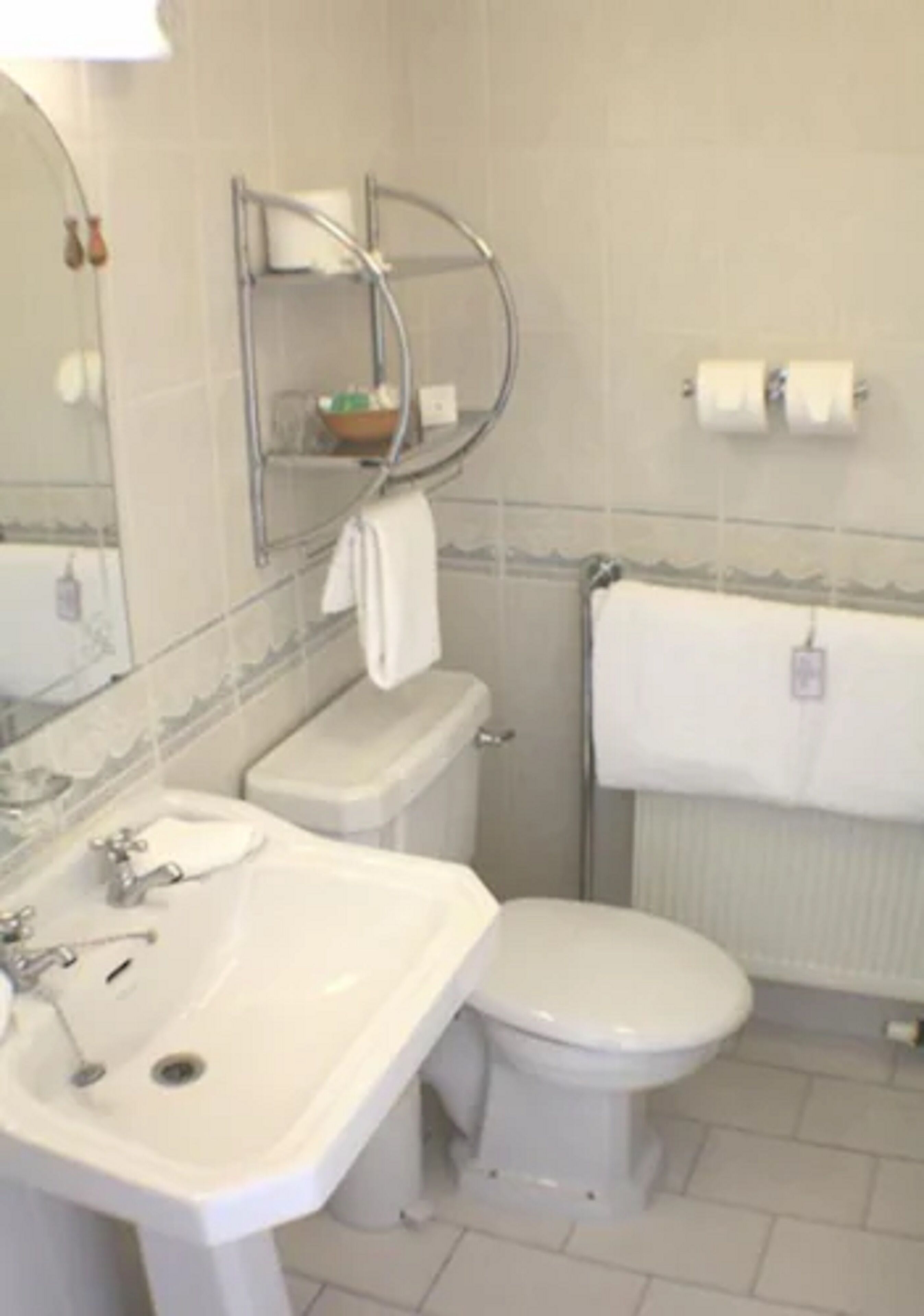 Een badkamer met een wit wastafelmeubel, toilet en een douchecabine van glas.