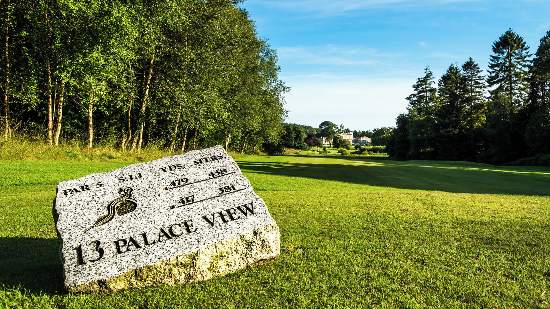 A sign indicating a 13th hole on a golf course with a view of a palace.