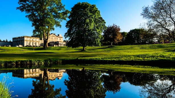 A large, historic building with a reflection in a pond, surrounded by well-maintained lawns and trees. - Cally Palace Hotel & Golf Course (Castle Douglas)