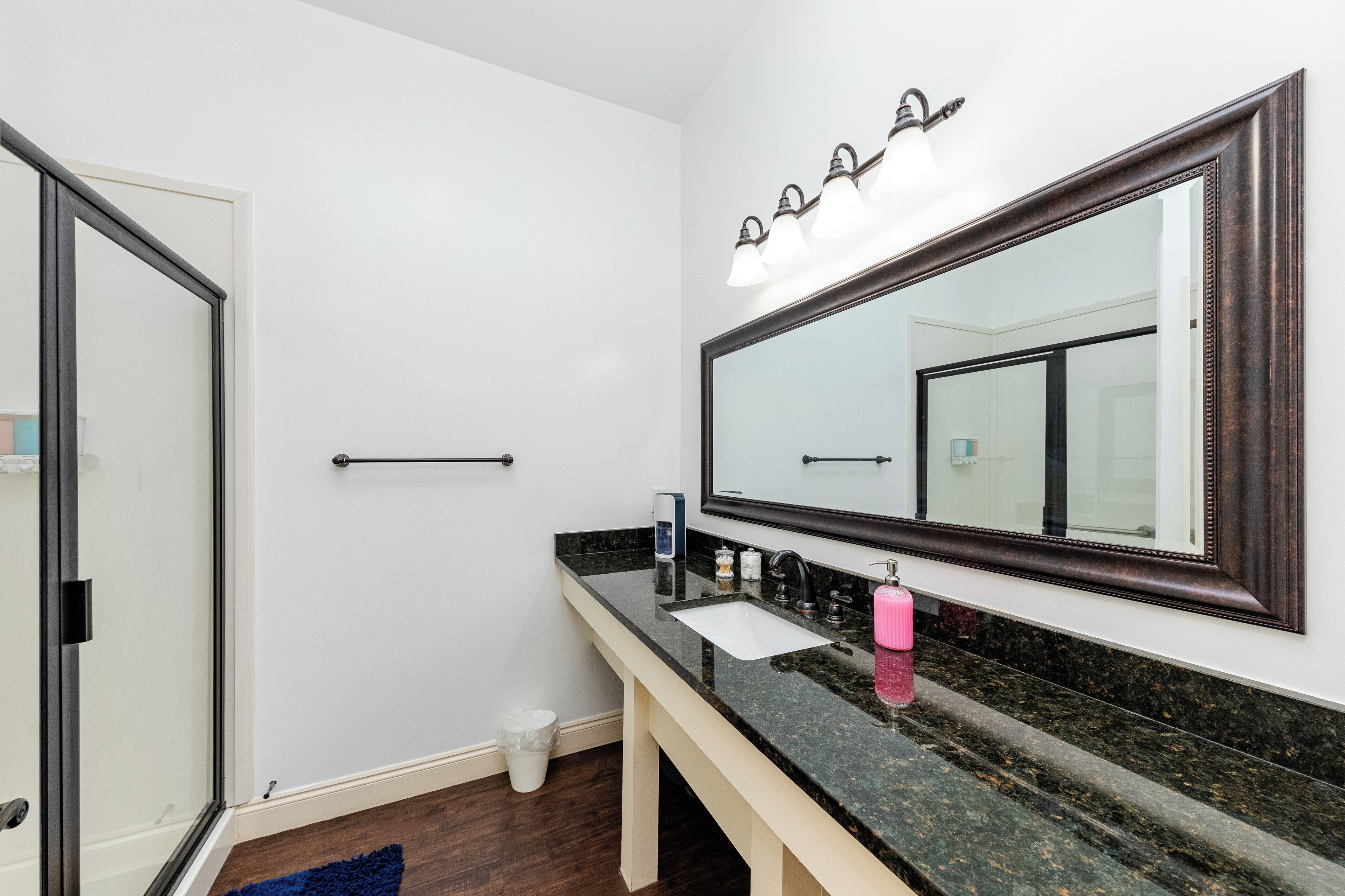 A bathroom with a large mirror, a sink, and a shower area.