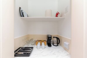 A kitchen with a coffee maker, tea kettle, and glassware on the counter. - 30A Inn & Suites (Santa Rosa Beach)
