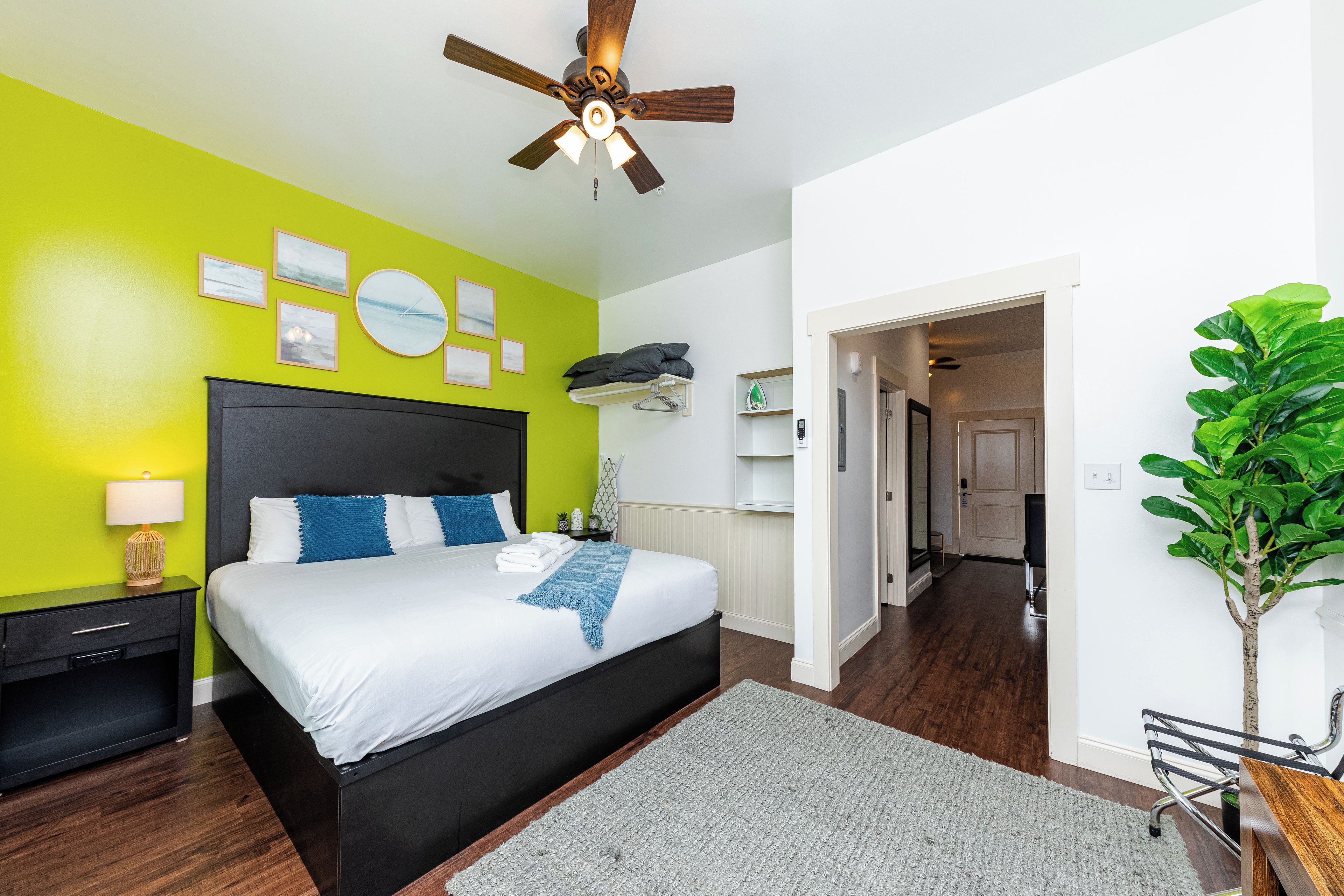 A modern bedroom with a bed, a nightstand, a bedside table, a wall clock, and a ceiling fan.