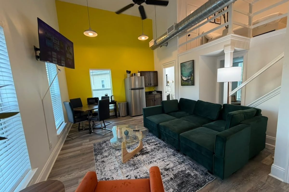 A modern living room with a green sofa, a coffee table, and a ceiling fan.