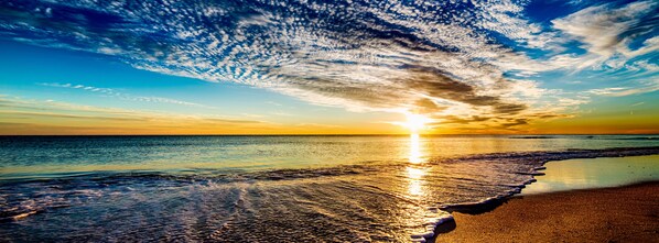 A beach scene with a sunset, waves, and a clear sky. - 30A Inn & Suites (Santa Rosa Beach)
