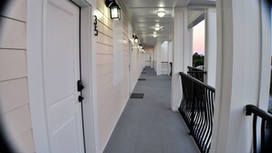 A corridor with white doors, black railings, and a grey carpet. - 30A Inn & Suites (Santa Rosa Beach)
