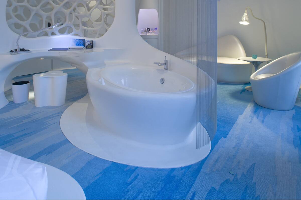 Un baño moderno con una bañera grande, un espejo redondo y un lavamanos contemporáneo.