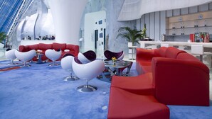 A modern interior with red seating, a large white structure, and hanging lights.
